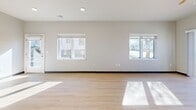 This single-floor residence in Sheboygan, Wisconsin offers a clean, modern aesthetic with a well-planned layout across a comfortable footprint. Light-toned hardwood-style flooring runs throughout the main living areas and bedrooms, complemented by neutral gray and white walls that lend a bright, contemporary feel.

The open-concept kitchen and living area serves as the heart of the unit. The kitchen features white cabinetry with brushed hardware, a generous white quartz peninsula with an undermount sink, pendant lighting, and white appliances including a range, microwave, and refrigerator. A window above the kitchen provides natural light and exterior views, while an adjacent balcony door connects to an outdoor space.

The living room benefits from two large windows that draw in abundant natural light and offer neighborhood views. An entry area includes a double closet for added storage convenience.

Both bedrooms feature the same light flooring and neutral walls, with wire-rack closet systems providing organized storage. The two bathrooms are finished consistently with large-format tile flooring, white vanities with quartz countertops, framed mirrors, and full bathtub-shower combinations, offering a cohesive and functional design throughout.