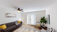 This single-floor space is thoughtfully designed with a clean, modern aesthetic throughout. The living room serves as the heart of the unit, featuring light hardwood flooring, crisp white walls, and a ceiling fan with integrated lighting. Natural light filters through French doors fitted with horizontal blinds, creating a warm and inviting atmosphere. The open layout connects seamlessly to the kitchen and dining areas, offering a practical and cohesive flow.

The kitchen is efficiently designed with white cabinetry, stainless steel appliances including a French-door refrigerator and dishwasher, and a wall-mounted mini-split air conditioning unit for independent climate control. A media console area near the entry provides additional functionality.

The bedroom is a calm, well-lit retreat with a ceiling fan, a wall-mounted mini-split unit, and a window dressed with blinds. A doorway leads directly into a walk-in closet with built-in hanging storage, adding notable convenience.

The bathroom features a tub-shower combination with stylish patterned curtains, a wall-mounted vanity with a single sink, and a window that brings in natural light. Hardwood flooring runs consistently throughout the main living areas, tying the space together with a cohesive, contemporary feel.