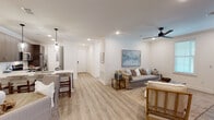This single-floor residence offers a thoughtfully designed open-concept layout across two bedrooms and two bathrooms. Light-toned hardwood-style flooring flows continuously throughout, unifying the living, dining, and kitchen areas under crown molding-trimmed ceilings fitted with recessed lighting and ceiling fans.

The living area is bright and inviting, with natural light entering through multiple windows dressed in white plantation shutters. Crown molding and a sleek ceiling fan add refined detail to the space.

The kitchen features dark espresso cabinetry with brushed hardware, white quartz countertops, a tile backsplash, and stainless steel appliances including an electric range and built-in microwave. A peninsula with bar seating and pendant lighting connects the kitchen to the dining area, with clear sightlines extending into the living room.

Both bedrooms are generously sized with hardwood-style flooring, recessed lighting, and ample natural light. The primary bathroom includes a double-sink vanity with dark cabinetry and white quartz counters, a large framed mirror, and a glass-enclosed walk-in shower with tile surround.

The overall aesthetic is clean and contemporary, with a warm, neutral palette throughout.