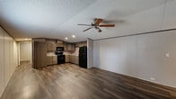 Located at 382 GA Highway 125 South in Tifton, Georgia, this single-floor, 3-bedroom, 2-bathroom home offers a practical and cohesive layout designed for comfortable everyday living. Dark wood-look vinyl plank flooring runs consistently throughout the home, creating a warm and unified aesthetic.

The open-concept main living area seamlessly combines the living room, dining room, and kitchen into one inviting space. The kitchen is a standout feature, showcasing warm-toned wood cabinetry, light stone-look countertops, a double-basin sink, and a striking stacked stone tile backsplash. Black appliances — including a refrigerator, range, and over-the-range microwave — complete the functional cooking space. Ceiling fans with integrated lighting are found in the living area and bedrooms, adding both comfort and practicality.

The three bedrooms are well-proportioned, featuring neutral wall paneling, textured ceilings, and windows with blinds that allow for natural light. The primary bedroom includes a dedicated closet with a hanging rod. A hallway connects the bedrooms to the two bathrooms, each equipped with a tub-shower combination featuring white tile surrounds and handheld showerheads. A dedicated laundry area and additional closet space round out the home's functional floor plan.