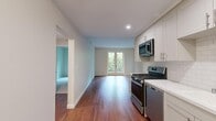 Located at 111 N Madison Ave in Pasadena, CA, this thoughtfully designed one-bedroom, one-bathroom residence offers a well-organized single-level floor plan that maximizes every inch of its compact footprint. Rich hardwood flooring flows throughout the main living areas, creating a warm and cohesive aesthetic from room to room.

The combined kitchen and living area serves as the heart of the home. The kitchen is outfitted with crisp white shaker cabinetry, white subway tile backsplash, light countertops, and a full suite of stainless steel appliances including a gas range, over-the-range microwave, dishwasher, and refrigerator. The adjoining living area benefits from natural light and leads to elegant French doors that open to a view of mature greenery, lending the space an airy, connected feel.

The bedroom is carpeted for comfort and features a window framing peaceful tree-lined views, along with a dedicated closet offering built-in shelving for organized storage. The bathroom is clean and well-appointed, showcasing a tiled shower-tub combination with polished chrome fixtures and floor-to-ceiling subway tile surround. A hallway connects the rooms efficiently, completing this practical and polished Pasadena residence.