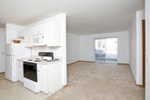 This single-floor unit offers a functional and comfortable layout across several well-defined living spaces. The living room is generously proportioned, featuring neutral carpet flooring, warm wood-toned baseboards, and a sliding glass door fitted with vertical blinds that invites natural light and provides access to an outdoor area. An adjacent open area extends the living space, offering flexibility for dining or lounging arrangements.

The galley-style kitchen is efficiently designed with ample white cabinetry lining both sides, providing abundant storage. It includes a double-basin sink, a coil-top electric range, a built-in microwave, a refrigerator, and track lighting overhead. Light tile flooring completes the clean, practical aesthetic.

Two carpeted bedrooms each feature ceiling fans with integrated lighting, windows with horizontal blinds that allow natural light, and warm wood-trimmed accents. One bedroom offers direct access to a full bathroom, creating a private en-suite feel.

The unit includes two bathrooms. The primary bathroom features a tub-shower combination, a toilet, a single vanity, a large mirror, and overhead cabinetry for storage. The secondary bathroom provides a vanity with sink, toilet, and a tub-shower, finished in a clean, neutral palette throughout.