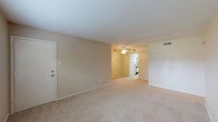 This single-floor residence offers a functional and comfortable layout designed for everyday living. The spacious living area is finished with wall-to-wall carpeting in a neutral beige tone, creating a warm and cohesive aesthetic throughout. Large windows allow natural light to fill the space, complemented by clean white trim and smooth ceilings.

The galley-style kitchen features white cabinetry, granite-look countertops, a white electric range, a dishwasher, and light tile flooring. An overhead exhaust fan and ample cabinet storage make the kitchen both practical and efficient. The kitchen opens directly into the living and dining area, supporting an easy flow between spaces.

The bedrooms are generously sized, each equipped with ceiling fans with integrated lighting and windows with horizontal blinds that provide natural light and outdoor views. The carpeted floors and neutral wall tones give each room a calm, versatile character.

The full bathroom includes a bathtub with shower, a toilet, a single-basin vanity with granite-look countertops, white cabinetry, and a wall-mounted medicine cabinet. The light tile flooring ties the space together neatly. A hallway connects the bedrooms and bathroom, with additional doors suggesting closet or storage access throughout. The overall design is clean, practical, and move-in ready.
