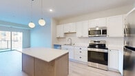 Located in Victoria, MN, this well-appointed one-bedroom, one-bathroom residence offers a thoughtfully designed layout across a single floor. The open-concept kitchen and living area serves as the heart of the home, featuring crisp white shaker cabinetry, a subway tile backsplash, stainless steel appliances including a refrigerator, range, microwave, and dishwasher, and a central island with a light quartz countertop and warm wood-toned base. Globe pendant lights add a modern touch overhead, while light hardwood-style flooring flows throughout the main living areas. The living room is bright and airy, with sliding glass doors opening onto a private balcony with views of the surrounding neighborhood. The bedroom is a comfortable retreat, carpeted in soft gray tones, with a ceiling fan and a window that allows natural light to fill the room. Two closets provide generous storage. The full bathroom is cleanly finished with light hardwood-style flooring, taupe shaker-style cabinetry, a white countertop vanity, and a tub-shower combination. Additional practical spaces include an in-unit laundry area and a utility room, rounding out the functional and modern character of this residence.