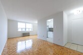 Located at 2441 Finch Avenue W in Toronto, this 2-bedroom, 1-bathroom unit offers a well-organized layout across a single floor. The living room is a bright, open space highlighted by warm parquet flooring that runs throughout the unit, crisp white walls, and large windows fitted with radiator heating that allow natural light to fill the room while offering views of the surrounding cityscape.

The kitchen is efficiently designed, featuring white cabinetry with modern bar-pull hardware, stone-effect countertops, a stainless steel sink, and a neutral tile backsplash. Tile flooring extends through the hallway, providing a clean transition between spaces.

The primary bedroom is a generously sized room with parquet flooring, a large window overlooking the city, and a built-in mirrored sliding closet that enhances the sense of space. The second bedroom is equally well-lit, with its own window and radiator, offering a comfortable and functional space.

The bathroom is finished with light beige wall tiles surrounding a full soaking tub and shower, complemented by a vanity with mirrored medicine cabinet and tile flooring. Throughout the unit, the clean, neutral palette and consistent flooring create a cohesive and practical living environment.
