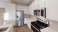 Located at 151 E Blount Ave in Knoxville, Tennessee, this well-appointed single-floor residence offers a clean, contemporary design with a neutral color palette and an efficient, open layout. The kitchen is a standout feature, showcasing white shaker-style cabinetry, subway tile backsplash, light quartz countertops, and a full suite of stainless steel appliances including a French door refrigerator, electric range, and over-the-range microwave. A center island with a double-basin sink provides additional prep space and flows seamlessly into the living and dining area, which is brightened by natural light and access to a balcony through glass-paned French doors. A ceiling fan adds comfort to this open living space. Hardwood-style flooring runs throughout the main living areas, while plush carpet adds warmth to the bedrooms. Each bedroom is generously sized, fitted with a ceiling fan and large windows that allow ample natural light and offer views of the surrounding cityscape. The primary bathroom features a glass-enclosed walk-in shower with white subway tile, a vanity with white cabinetry, and a spacious walk-in closet. A second full bathroom is similarly finished with a white vanity, mirror, and walk-in shower. The overall ambiance is bright, modern, and move-in ready.
