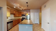 This single-floor residence offers a functional and cohesive layout highlighted by a well-appointed kitchen at its heart. The kitchen is outfitted with warm honey-toned cabinetry, granite-look countertops, and a full suite of stainless steel appliances, including a refrigerator, range, microwave, and dishwasher. A center island provides additional prep and dining space, while a combination of track lighting and a pendant light ensures ample illumination throughout. Light tile flooring completes the kitchen's practical aesthetic.

The living area features wood-look plank flooring and neutral wall tones, creating a calm and versatile backdrop. Sliding glass doors open to a private balcony, bringing in natural light and outdoor views. Additional rooms continue the wood-look flooring theme and benefit from multiple windows fitted with horizontal blinds, allowing for adjustable natural light.

The bathroom includes a soaking tub with tile surround, a shower fixture, and tile flooring, offering a clean and comfortable design. Notably, a walk-in closet is accessible directly from the bathroom, adding a convenient storage solution. Throughout the space, a consistent neutral palette and practical finishes create a cohesive, move-in-ready environment.