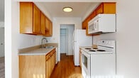 This single-story unit is thoughtfully arranged to maximize functionality across its living spaces. The galley-style kitchen is a central feature, lined on both sides with warm honey-toned wood cabinetry offering generous upper and lower storage. White appliances, including a refrigerator, electric range, over-the-range microwave, and dishwasher, are integrated throughout. Neutral laminate countertops and a single-basin sink complete the workspace, while wood-look flooring runs underfoot and natural light filters in, adding warmth to the corridor-style layout. A walk-in closet or pantry is accessible directly from the kitchen.

The living area is generously proportioned, carpeted in a neutral beige tone, and filled with natural light through both a side window and a large sliding glass door fitted with vertical blinds. A ceiling fan serves the space, and the open layout connects fluidly to the kitchen via a partial-wall passthrough.

The bedrooms are each carpeted and bright, with windows allowing natural light. Closet storage is present in the bedrooms, including at least one with a reach-in closet configuration. The overall palette throughout is clean and neutral, creating a bright, move-in-ready atmosphere.
