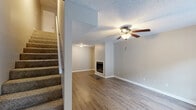 Located at 1902 Brady Dr in Dalton, GA, this two-story home offers a well-organized layout spread across two floors. The main level features an open living area with hardwood-style flooring, a ceiling fan, and natural light from a front-facing window. A standout fireplace with tile surround anchors one end of the living space, adding warmth and character. The kitchen is equipped with stainless steel appliances, white cabinetry, a tile backsplash, and ample counter space, complemented by a window overlooking the outdoors. Sliding doors provide access to additional storage areas on this floor. Upstairs, two carpeted bedrooms offer comfortable retreats, each with windows that frame views of surrounding greenery. The primary bedroom features sliding closet doors and neutral tones throughout. Both bathrooms are functional and well-appointed — one includes a vanity with a marbled countertop and large mirror, while the other features a tub/shower combo and wood-style flooring. A hallway and staircase connect the floors efficiently. Outside, a spacious wood deck with railings overlooks a lush, tree-lined backyard, offering a peaceful setting for outdoor relaxation. Textured ceilings are consistent throughout the home.