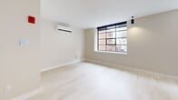 Located at 31 Pratt Street in the heart of Hartford, CT, this efficiently designed studio unit offers a clean, contemporary living experience across a single floor. The open layout is bright and airy, anchored by light-toned hardwood flooring and neutral walls that create a welcoming, minimalist ambiance throughout.

The living area features a striking black-framed picture window that frames views of the surrounding Hartford cityscape, flooding the space with natural light. A wall-mounted split HVAC unit ensures year-round comfort, while recessed and pendant lighting add functional and aesthetic illumination.

The kitchen is a standout feature, thoughtfully outfitted with crisp white shaker cabinetry, light quartz countertops, and a classic subway tile backsplash. Stainless steel appliances — including a refrigerator, electric range, over-the-range microwave, and dishwasher — complete this well-appointed culinary space. The black hardware accents throughout lend a modern, cohesive touch.

The bathroom is neatly finished with a tiled walk-in shower featuring a marble-look threshold, matte black fixtures and towel bars, and neutral tile walls that contribute to a clean, spa-like aesthetic.

Overall, this unit combines smart design with quality finishes, making it an ideal urban retreat in downtown Hartford.