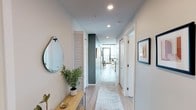 Located at 206 E Fillmore St in the heart of Phoenix, this single-floor residence showcases a thoughtfully designed modern interior with clean lines and contemporary finishes. The entry hallway sets an inviting tone, featuring light wood-style flooring, recessed lighting, a decorative mirror, and a runner rug that guides you into the main living areas.

The living room is a standout space, anchored by expansive floor-to-ceiling windows on two sides that flood the room with natural light and frame striking panoramic views of the downtown Phoenix skyline. A ceiling fan, exposed concrete columns, and light hardwood flooring contribute to the unit's urban-modern aesthetic.

The kitchen is well-appointed with dark wood cabinetry extending to the ceiling, a large island with white quartz countertops, a gas cooktop with a stainless steel range hood, a French door refrigerator, and ample storage throughout.

The bedroom continues the modern theme with floor-to-ceiling windows, exposed concrete detailing, and generous natural light. The bathroom is spacious and clean, featuring a double-sink vanity with dark cabinetry, light tile flooring, and a glass-enclosed walk-in shower. The overall ambiance throughout is contemporary, bright, and urban.
