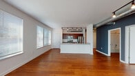 This one-bedroom, one-bathroom residence at The Delta in Memphis, Tennessee combines modern urban design with industrial-inspired details throughout its single-story layout. The living area is a standout feature, showcasing polished concrete floors that extend throughout the entire unit, lending the space a sleek, loft-like aesthetic. Track lighting runs along the ceiling, providing both ambient and directed illumination, while an exposed metal ductwork element adds an industrial character to the open living and dining area. A large set of windows fitted with white blinds allows natural light to fill the main living space, complementing the neutral wall tones and a bold charcoal accent wall that adds visual depth.

The kitchen is outfitted with rich, dark wood cabinetry, granite countertops, and stainless steel appliances, including a range and over-the-range microwave. A peninsula counter connects the kitchen to the main living area, enhancing the open-concept flow of the space.

The bathroom is clean and functional, featuring a granite-topped vanity with dark wood cabinetry, a full tub-shower combination, and brushed nickel fixtures. The consistent use of polished concrete flooring carries into the bathroom, maintaining a cohesive design throughout the unit.