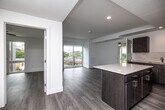 Located at 637–651 E Walnut St in Des Moines, Iowa, this well-appointed 2-bedroom, 2-bathroom residence offers a thoughtfully designed single-level layout with a clean, contemporary aesthetic throughout. Light-toned hardwood-style flooring flows seamlessly across the entire space, complementing the bright white walls and recessed lighting that give every room an open, airy feel.

The open-concept kitchen and living area serves as the heart of the home. The kitchen is outfitted with rich dark wood cabinetry, a tile backsplash, white quartz countertops, and a full suite of stainless steel appliances including a refrigerator, range, microwave, and dishwasher. A central island provides additional prep space and casual seating. The living area extends naturally from the kitchen and opens via sliding glass doors onto a private balcony, offering pleasant views of the surrounding neighborhood.

The primary bedroom is a well-proportioned retreat with ample natural light, while the second bedroom is equally bright and functional. Both bedrooms feature the same consistent flooring and neutral palette found throughout the space. A frosted glass door adds a modern architectural detail near the entry.

The two bathrooms are finished with matching dark vanity cabinetry, white quartz countertops, large framed mirrors, and hardwood-style flooring. One bathroom features a tub-shower combination, providing practical functionality with a clean, modern finish.