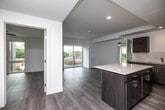 Located at 637–651 E Walnut St in Des Moines, Iowa, this well-appointed 2-bedroom, 2-bathroom residence offers a thoughtfully designed single-level layout with a clean, contemporary aesthetic throughout. Light-toned hardwood-style flooring flows seamlessly across the entire space, complementing the bright white walls and recessed lighting that give every room an open, airy feel.

The open-concept kitchen and living area serves as the heart of the home. The kitchen is outfitted with rich dark wood cabinetry, a tile backsplash, white quartz countertops, and a full suite of stainless steel appliances including a refrigerator, range, microwave, and dishwasher. A central island provides additional prep space and casual seating. The living area extends naturally from the kitchen and opens via sliding glass doors onto a private balcony, offering pleasant views of the surrounding neighborhood.

The primary bedroom is a well-proportioned retreat with ample natural light, while the second bedroom is equally bright and functional. Both bedrooms feature the same consistent flooring and neutral palette found throughout the space. A frosted glass door adds a modern architectural detail near the entry.

The two bathrooms are finished with matching dark vanity cabinetry, white quartz countertops, large framed mirrors, and hardwood-style flooring. One bathroom features a tub-shower combination, providing practical functionality with a clean, modern finish.