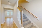 Located at 4097 General Parkway in College Station, TX, this two-story home offers 4 bedrooms and 4 bathrooms across two well-appointed floors. The main floor hosts the primary living areas, including an open-concept living room, dining area, and kitchen. The kitchen is a standout, featuring dark cabinetry, a large white quartz island with an undermount sink, stainless steel appliances, subway tile backsplash, and an industrial-style pendant light fixture. Light hardwood flooring flows throughout the main level, complementing the bright, white walls and recessed lighting. The living room showcases a decorative board-and-batten accent wall, adding a modern farmhouse touch. A staircase with carpeted treads, white balusters, and a warm wood handrail connects the two floors. The upper level contains additional bedrooms with plush carpet, ceiling fans, and dedicated closets. Bathrooms are finished with dark cabinetry, white countertops, matte black fixtures, and tile surround tub-shower combinations. The home also includes a pantry, laundry room, and ample hallway and closet space, offering functional storage throughout. The overall aesthetic is clean, contemporary, and move-in ready.