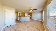 Located at 943 Hamilton Falls in Catoosa, Oklahoma, this two-story home offers 2 bedrooms, 2 bathrooms, and a thoughtfully arranged layout spread across two floors. The main level features an open-concept living area with light wood-look flooring, recessed lighting, and a ceiling fan, creating a bright and welcoming atmosphere. The kitchen is a functional highlight, featuring warm honey-toned cabinetry, granite-style countertops, a tile backsplash, a peninsula with bar-height seating potential, and appliances including a range, microwave, dishwasher, and refrigerator. A pedestal sink bathroom with built-in shelving and tile flooring is also found on this level, alongside a dedicated laundry area. Upstairs, both bedrooms are finished with plush carpet and ceiling fans, with the primary bedroom offering generous proportions, natural light through a large window, and access to a well-sized closet with dual hanging rods. The upper-level full bathroom includes a vanity with wood cabinetry, tile flooring, and a tub-shower combination. Additional closet and hallway space provides practical storage throughout. The home's neutral palette and consistent finishes lend a clean, move-in-ready appeal.