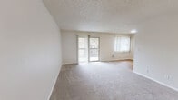 Located at 6407 S 12th St in Tacoma, WA, this one-bedroom, one-bathroom unit offers a functional and comfortable single-floor layout. The living area is bright and open, featuring neutral wall-to-wall carpeting and two large windows dressed with vertical blinds, one of which opens to a private balcony, allowing natural light to fill the space. A textured ceiling adds classic character throughout the living and bedroom areas. The galley-style kitchen is efficiently designed with warm honey-toned wood cabinetry offering ample upper and lower storage, white laminate countertops, a stainless steel sink, and white appliances including a refrigerator and electric range. Light hardwood-style flooring runs throughout the kitchen, lending a clean, cohesive look. The bedroom is a comfortable size, outfitted with plush carpeting, a window with blinds, and a dedicated closet providing practical storage. The full bathroom features a single-sink vanity with matching wood cabinetry, a tub-shower combination, and hardwood-style flooring, maintaining a consistent, clean aesthetic. The overall ambiance of the unit is neutral, clean, and move-in ready, making it a practical and comfortable home in Tacoma.