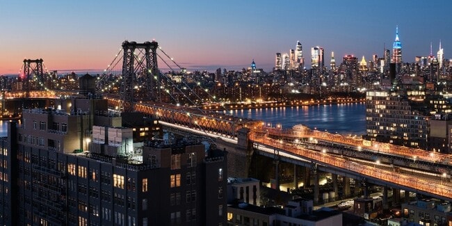 A stunning view of the Williamsburg Bridge, illuminated by the Manhattan skyline