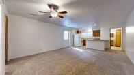 Located at Belmont St in Liberty, MO, this single-floor unit offers a practical and functional layout designed to maximize its compact footprint. The open-concept living and kitchen area forms the heart of the space, with soft carpet flooring throughout the living zone and a ceiling fan with integrated lighting overhead. Neutral white walls and a textured ceiling contribute to a clean, understated aesthetic.

The kitchen is well-equipped, featuring warm-toned oak cabinetry, a peninsula counter with a granite-style surface that separates it from the living area, white appliances including a refrigerator, electric range, and dishwasher, as well as a double stainless steel sink beneath a window that allows natural light into the space. Light wood-look vinyl plank flooring runs through the kitchen, offering a practical and durable surface. A secondary door provides direct exterior access from the main living area.

The bathroom continues the cohesive design with the same light vinyl plank flooring, warm wood cabinetry, a granite-style vanity countertop, a wood-framed mirror, and a toilet. The space is ventilated by an overhead vent. A dedicated closet with a wood-panel door provides convenient storage. This unit offers a straightforward, move-in-ready layout suited for efficient everyday living.