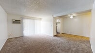 Located at 1502 Jellick Ave in Rowland Heights, CA, this single-story unit offers a straightforward, functional layout across several well-defined spaces. The open living area is finished with wall-to-wall carpet and features large sliding glass doors dressed with vertical blinds, allowing generous natural light to fill the room. A ceiling fan is positioned in the adjoining area, providing airflow and additional lighting. The textured popcorn ceilings are consistent throughout the carpeted zones, lending a classic residential character to the interior. The kitchen is equipped with dark wood-style vinyl flooring, white cabinetry, laminate countertops, and black appliances including a coil-top electric range and an over-the-range microwave. A window with vertical blinds provides natural light to the cooking space. The bedroom is generously sized with plush carpet flooring, neutral white walls, a textured ceiling, and a window fitted with vertical blinds that brings in outside light. The bathroom features a wide vanity with a granite-style countertop, white cabinetry with brushed nickel hardware, a large mirror, wood-style vinyl flooring, and a clean white tub and shower combination. The overall palette throughout the unit is neutral and bright, creating a clean, move-in ready environment.
