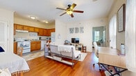 This one-bedroom, one-bathroom apartment at Savannah Square in Auburn, Alabama offers a practical and comfortable single-floor layout thoughtfully designed to maximize functionality. The open living area features warm hardwood flooring and a ceiling fan overhead, creating an inviting atmosphere that flows seamlessly into the kitchen. Natural light filters through windows, enhancing the bright, neutral color palette throughout.

The kitchen is well-appointed with warm-toned wood cabinetry, ample counter space, and a full suite of white appliances including a range, dishwasher, refrigerator, and microwave. A classic checkered tile floor adds a distinct character to the space. Crown molding and louvered closet doors add a refined touch to the kitchen area.

The bedroom is a relaxing retreat, featuring plush carpeting, a ceiling fan, and a window that brings in natural light. A closet and direct access to the full bathroom add to the room's convenience.

The bathroom includes a single-sink vanity with wood cabinetry, a tiled tub-shower combination, and a high window that provides ventilation and light while maintaining privacy. The checkered flooring ties the bathroom's design back to the kitchen, creating a cohesive aesthetic throughout the unit. This apartment is ideally situated for Auburn University students or professionals seeking comfortable living in Auburn, AL.