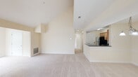 Located at 9095 Thamesmeade Rd in Laurel, Maryland, this single-floor residence offers a thoughtfully designed layout with a bright, open ambiance throughout. The living area is immediately distinguished by dramatically vaulted ceilings that create a strong sense of spaciousness and volume. A tile-surround fireplace serves as a central focal point, flanked by multiple windows that invite generous natural light and views of surrounding greenery. Plush wall-to-wall carpeting extends across the living spaces, contributing to a warm, comfortable atmosphere.

The kitchen is positioned adjacent to the living area and features warm wood cabinetry, dark granite-style countertops, tile flooring, and stainless steel appliances including a range, over-the-range microwave, and refrigerator. A raised breakfast bar provides a functional transition between the kitchen and the open living space.

The bedrooms are carpeted and well-proportioned, with one room showcasing angled ceilings and a ceiling fan, adding architectural interest. Windows overlook mature trees, enhancing the sense of privacy. The bathrooms include a full bath with a tub-shower combination and tile flooring, and a second bath with a walk-in shower, both finished with wood vanities and brushed nickel fixtures.
