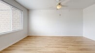 Located at 413 Tenth Ave in Coralville, Iowa, this efficiently designed studio offers a thoughtful layout that maximizes every square foot. The open-plan kitchen and living area forms the heart of the space, finished with light wood-tone flooring that runs consistently throughout, lending a warm, cohesive feel. The kitchen is well-appointed with white shaker-style cabinetry featuring black hardware, light quartz-style countertops, and a full suite of stainless steel appliances including a refrigerator, electric range, over-the-range microwave, and dishwasher. A large window with blinds fills the kitchen with natural light and provides outdoor views. The living area benefits from a ceiling fan with light fixture, a wall-mounted mini-split HVAC unit for year-round comfort, and additional natural light from windows fitted with blinds. The bathroom is clean and modern, featuring a white vanity with black hardware, matching the kitchen's aesthetic, alongside light wood-look flooring and crisp white walls. A built-in closet with paneled doors provides practical storage. Recessed lighting and white walls throughout the unit create a bright, airy atmosphere that enhances the sense of space.