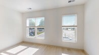 Located at 106 S Buchanan St in Spring Lake, Michigan, this efficiently designed unit offers a clean, modern aesthetic throughout its single-floor layout. Light-toned luxury vinyl plank flooring runs continuously throughout the space, enhancing the bright and airy atmosphere created by large windows that invite abundant natural light and provide views of the surrounding area.

The kitchen is a standout feature, appointed with stainless steel appliances including an electric range, over-the-range microwave, refrigerator, and dishwasher. Light or dark wood cabinetry — depending on the unit configuration — pairs with crisp white quartz countertops and a classic white subway tile backsplash, delivering a polished, contemporary look. The kitchen flows directly into the open living area, creating a seamless and functional living space.

The main living area is generously proportioned relative to the unit's overall footprint, with tall ceilings and clean white walls that amplify the sense of openness. Two louvered doors provide access to closet storage, while an additional door leads to a utility area housing stacked in-unit laundry. Recessed lighting and an electrical panel are neatly integrated. The overall ambiance is fresh, minimal, and move-in ready, making this Spring Lake unit an efficient and stylish place to call home.