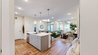 This well-appointed 2-bedroom, 2-bathroom residence offers a thoughtfully designed open-concept layout that seamlessly connects the kitchen, dining, and living areas. The modern kitchen is a standout feature, showcasing gray shaker cabinetry, a quartz waterfall island with bar seating, stainless steel appliances, a subway tile backsplash, and pendant lighting — all set atop warm hardwood-style flooring. The dining area is bathed in natural light from transom windows and a sliding glass door that opens to a private balcony with greenery views. The living room continues the bright, airy feel with large windows, recessed lighting, and clerestory windows that draw in additional light. The primary bedroom is a comfortable retreat featuring a ceiling fan, plush carpet, and a window overlooking lush outdoor scenery. The second bedroom offers flexibility as a home office or guest room, complete with ample natural light and carpet flooring. Both bathrooms are finished with gray vanities and quartz countertops, with one featuring a soaking tub. Additional conveniences include two closets and an in-unit laundry area equipped with a full-size washer. The overall ambiance is clean, contemporary, and inviting throughout.