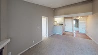 This single-floor unit offers a well-organized and functional layout designed to maximize comfort and usability. The living area is a standout feature, boasting vaulted ceilings that lend a sense of spaciousness and openness to the room. Warm, neutral-toned walls complement the plush carpeting underfoot, creating an inviting atmosphere throughout. A seamless transition leads from the living space toward the entry area, where hardwood-style flooring adds warmth and durability.

The galley-style kitchen is efficiently designed, featuring white cabinetry with ample storage, laminate countertops, a stainless steel sink, a full-size refrigerator, and an electric range — all arranged to make the most of the available space. The kitchen connects conveniently to the main living and dining area via a pass-through counter, enhancing the open feel of the unit.

The bedroom is generously sized, carpeted for comfort, and includes a closet with louvered doors, offering practical storage solutions. A full bathroom serves the unit, complete with a tub and shower combination, a toilet, and clean white finishes throughout. Textured ceilings are present across the unit, adding a classic residential character to the overall design.