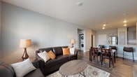 Located on Grand Vista Circle in Colorado Springs, Colorado, this single-floor residence offers a thoughtfully designed layout with modern finishes throughout. The open-concept living and dining area serves as the heart of the unit, featuring wood-look plank flooring, neutral gray walls, and a seamless flow toward the kitchen. A dedicated in-unit laundry closet with a stacked washer and dryer is conveniently accessible from the main living space.

The kitchen is well-equipped with stainless steel appliances—including a refrigerator, range, microwave, and dishwasher—complemented by gray shaker-style cabinetry and granite-style countertops. Natural light filters into the living area through a window fitted with horizontal blinds.

Both bedrooms are carpeted and feature ceiling fans, windows with blinds, and a calm, neutral color palette. One bedroom includes an en-suite bathroom with direct access to a walk-in closet. The bathrooms are finished with gray vanity cabinetry, granite-topped counters, wood-look flooring, and tiled tub-shower combinations. A large vanity mirror adds brightness to each bathroom.

Overall, the unit presents a clean, contemporary aesthetic with consistent finishes, functional spaces, and practical amenities throughout.