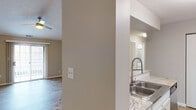 This single-story residence is designed with an open, airy layout highlighted by vaulted ceilings in the living area, which lend a sense of generous vertical space. The living room serves as the central gathering space, anchored by a tile-surround fireplace and outfitted with a ceiling fan overhead. Sliding glass doors provide access to the exterior, allowing natural light to fill the room. Wood-look plank flooring runs throughout the main living areas, offering a clean, cohesive aesthetic.

The kitchen is well-appointed with white shaker cabinetry, granite-style countertops, a decorative tile backsplash, and stainless steel appliances including a refrigerator and electric range. A peninsula with bar seating opens the kitchen toward the living space, enhancing the open-concept flow. A stainless steel double sink with a pull-down faucet adds functional detail.

The bedrooms are comfortably sized, each featuring wood-look flooring and windows that admit natural light. Two full bathrooms serve the unit, each featuring a tub-shower combination, updated fixtures, granite-topped vanities, and tile flooring. The overall interior palette of neutral tones and modern finishes creates a clean, move-in ready environment throughout.