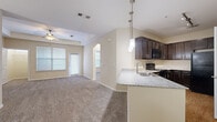 Located at 8585 Sienna Springs Dr in Missouri City, Texas, this single-floor residence offers a well-designed, open-concept layout that seamlessly connects the main living spaces. The kitchen is a standout feature, equipped with rich dark espresso cabinetry, granite countertops, a breakfast bar peninsula with pendant lighting, black appliances including a refrigerator and range, and hardwood-style flooring. Track lighting above the kitchen adds a modern touch, while the open sightlines into the living area create a welcoming, connected atmosphere. The living room is generously sized, finished with plush carpeting and a ceiling fan, and receives natural light through large windows fitted with blinds. An arched doorway adds a subtle architectural detail that transitions gracefully between spaces. The bedrooms feature soft carpeting, tray ceilings with ceiling fans, and bright windows that invite natural light. The primary bedroom includes a tray ceiling detail and direct access to a closet area. The bathroom is finished with hardwood-style flooring, dark cabinetry with a light countertop, and a full tub-shower combination with brushed nickel fixtures. Throughout the home, neutral warm-toned walls and clean white trim contribute to a bright, cohesive aesthetic.