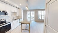 This 620 square foot apartment at 900 N Tryon offers a blend of comfort and contemporary design. The single-floor layout maximizes space efficiency, featuring one bedroom and an open-concept living area. The spacious primary bedroom, measuring 170 square feet, provides ample room and includes a walk-in closet for storage.

The living area is highlighted by large windows that flood the space with natural light, complemented by a modern electric fireplace. A ceiling fan enhances air circulation throughout. The kitchen boasts sleek white cabinetry, stainless steel appliances, and granite countertops, creating a stylish and functional cooking space.

The apartment's design incorporates light-colored walls and a mix of carpeted and hardwood-style flooring, contributing to a bright and airy atmosphere. A private balcony offers outdoor space and views of the surrounding area.

Additional features include in-unit climate control and proximity to community amenities such as a pool. The property is part of a multi-story residential complex, providing urban living with modern conveniences in a prime location.