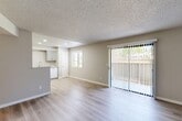Located at 1227 Corral Creek Ave in Paso Robles, CA, this single-floor residence offers 2 bedrooms and 2 bathrooms with a well-designed, functional layout. The open-concept living, dining, and kitchen area serves as the heart of the home, featuring light wood-style flooring, neutral warm-beige walls, and a textured ceiling. A full-width sliding glass door floods the living room with natural light and provides outdoor access. The kitchen is equipped with gray shaker-style cabinetry, light countertops, recessed lighting, a white appliance suite including a refrigerator, range, and dishwasher, and a peninsula that separates it from the living area. A pantry adds convenient storage. Both bedrooms are carpeted, bathed in natural light from large windows with blinds, and served by ample closet space — four closets total across the unit. The two bathrooms are finished consistently with gray vanity cabinetry, light countertops, wood-style flooring, and tub-shower combinations. A connecting hallway ties the private areas together efficiently. The overall aesthetic is clean, modern, and move-in ready, with a cohesive neutral palette throughout.