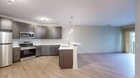 Located at 69 Marlborough St in Portland, Connecticut, this well-appointed single-floor residence offers a thoughtfully designed open-concept layout. Light-toned, wood-style flooring runs consistently throughout the space, creating a cohesive and modern aesthetic.

The kitchen is a standout feature, equipped with rich dark-brown cabinetry, stainless steel appliances including a refrigerator, range, microwave, and dishwasher, and crisp white countertops. A peninsula with an integrated sink and elegant pendant lighting overhead provides additional prep space and serves as a natural divider between the kitchen and the living area. The living room is bright and open, with a sliding glass door that leads to a private balcony offering views of the surrounding community and open sky.

The bedroom is a calm, neutral space with light walls, natural light from a window, and ample room for furnishings. Closet access is conveniently located nearby. The full bathroom features a tub-shower combination, a dark-cabinetry vanity with a white countertop and single sink, a large mirror, and brushed nickel fixtures throughout. Clean, neutral wall tones and consistent flooring tie the entire residence together for a fresh, move-in-ready feel.