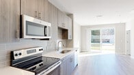 Located at 5540 Atlantic Springs Rd in Raleigh, NC, this modern single-floor residence showcases a clean, contemporary design with consistent light wood-style flooring and a neutral color palette throughout. The kitchen is a standout feature, outfitted with wood-grain cabinetry, quartz countertops, a subway tile backsplash, and a full suite of stainless steel appliances including a refrigerator with ice maker, electric range, over-the-range microwave, and dishwasher. A sliding glass door adjacent to the kitchen provides direct access to an outdoor area, filling the space with natural light. The bedrooms are generously proportioned, each featuring ceiling fans, wide windows with blinds for natural light control, and easy access to additional rooms. The bathroom offers a sleek, spa-like feel with a frameless sliding glass shower enclosure, white subway tile surround, wood-grain vanity, and matching flooring. A dedicated laundry area houses a stacked full-size washer and dryer, adding everyday convenience. The overall ambiance is bright, clean, and move-in ready, reflecting a thoughtfully designed modern living space.