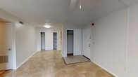 This single-floor unit offers a functional and well-organized layout across two bedrooms and two full bathrooms. The entryway greets residents with neutral-toned tile flooring that extends throughout the entire unit, providing a cohesive and easy-to-maintain surface underfoot. Near the front door, a dedicated entry closet offers convenient storage alongside an additional built-in shelving unit, ideal for organization.

The main living area is open and bright, featuring a ceiling fan with light fixture and access to the outdoors through a large window dressed with vertical blinds, allowing natural light to filter in. The galley-style kitchen is efficiently designed with honey-toned wood cabinetry on both sides, laminate countertops, a double-basin sink, and white appliances including a refrigerator and range.

Both bedrooms are well-proportioned, each equipped with a ceiling fan, a large window for natural light, and a sliding-door closet providing ample storage. The two full bathrooms are identically appointed, each featuring a tub-shower combination set within an arched niche, a wood-vanity with single sink, laminate countertop, and a large wall mirror with overhead lighting.