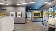 Located at 1201 Constitution Ave in Philadelphia, PA, this thoughtfully designed single-floor communal space offers a well-organized layout across four distinct functional areas. The entry zone features a dedicated mail room with an extensive array of built-in black mailboxes, complemented by a sculptural round pedestal table with a decorative vase, setting an inviting tone from the moment of arrival.

The lounge and collaboration area is a visual centerpiece, highlighted by a striking geometric acoustic ceiling installation in green and black tones that adds dramatic texture overhead. A warm wood communal table with contemporary seating anchors this zone, while floor-to-ceiling windows invite abundant natural light and provide views of the surrounding streetscape.

A series of glass-walled private workrooms line one corridor, each bathed in chartreuse-yellow accent lighting and equipped with individual workstations and seating—ideal for focused tasks or small meetings. Framed artwork along the hallway walls adds a cultivated, gallery-like quality to the passage between zones.

Throughout the space, a cohesive palette of cool grays, bold yellow-green accents, and dark trim creates a modern, energetic atmosphere. Linear pendant lighting and recessed fixtures maintain consistent, well-distributed illumination. Neutral carpeting unifies the floor plan, while built-in cabinetry with a wall-mounted display screen provides a practical media station within the communal area.