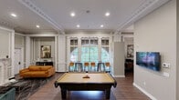 Located at 902 N Market St in the heart of Wilmington, Delaware, this thoughtfully designed single-floor space seamlessly combines classic architectural elegance with contemporary functionality. The expansive living room serves as the centerpiece, boasting soaring ceilings adorned with ornate crown molding and detailed wainscoting panels that line the walls. A striking marble fireplace anchors the room, complemented by rich hardwood flooring, large windows that flood the space with natural light, and access to an outdoor area. A full-size pool table and curated seating arrangements make this a versatile gathering space. The kitchen is well-appointed with stainless steel appliances, including a refrigerator, dishwasher, built-in microwave, and range, paired with granite countertops, a stainless steel sink, and ample cabinetry in a clean, neutral finish. The dedicated office area offers a quiet, paneled alcove with workstations equipped with computers and printing capabilities, accented by wainscoting consistent with the rest of the space. Throughout, the interiors reflect a refined aesthetic, with neutral tones, curated artwork, and a cohesive design language that honors the building's historic character while providing modern comfort.