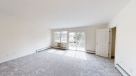 Located at 1100 Lake Drive in Medford, NY, Heatherwood at Medford Pond is a well-appointed multi-floor residence offering a thoughtfully designed layout spread across three levels. The main living area is bright and spacious, featuring plush wall-to-wall carpeting and large sliding glass doors that open to a private balcony, flooding the room with natural light and providing pleasant outdoor views. Baseboard heating and a wall-mounted air conditioning unit ensure year-round comfort in this welcoming space. The kitchen is equipped with rich wood cabinetry, white appliances including a refrigerator and dishwasher, and durable tile flooring. Multiple sliding-door closets and an in-unit washer and dryer add significant convenience and storage capacity. A carpeted staircase with a warm wood handrail connects the floors seamlessly. The bedroom is generously sized with plush carpeting and features a walk-in closet with built-in shelving, offering ample organization. The bathroom is clean and functional, appointed with a wide vanity, mirrored medicine cabinet with Hollywood-style lighting, tiled floors, and a glass-door combination tub and shower. Throughout the residence, a neutral color palette and clean finishes create a calm, move-in-ready atmosphere.