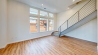 This contemporary two-story home in Richmond, Virginia offers a thoughtfully designed layout spread across two well-proportioned floors. The main level features an open-concept kitchen and living area bathed in natural light from large, floor-to-ceiling windows. The kitchen is a standout, boasting sleek white cabinetry extending to the ceiling, stainless steel appliances, a subway tile backsplash, and a striking quartz-topped island with bold veining — ideal for both cooking and entertaining. Light hardwood flooring flows throughout both levels, complementing the bright, neutral palette. A modern staircase with metal railings connects the floors with an industrial-chic touch. The main level also includes a convenient half bath with a wood-toned vanity and quartz countertop. Upstairs, the spacious primary bedroom offers generous square footage, a ceiling fan, and city views, accompanied by a walk-in closet featuring wire shelving systems. The additional bedroom is well-sized with built-in cabinetry and a ceiling fan. Three bathrooms in total include well-appointed full baths with glass-enclosed walk-in showers, tiled floors, and wood vanities with marble-style countertops. This home delivers a clean, modern aesthetic with quality finishes throughout.