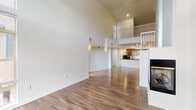 Located at 7596 E 29th Ave in Denver's vibrant Central Park neighborhood, this two-story residence showcases a thoughtfully designed open-concept layout with striking architectural details throughout. The main living area immediately impresses with soaring vaulted ceilings and large windows that flood the space with natural light, while wood-style flooring flows seamlessly throughout both levels.

The kitchen is well-appointed with light wood cabinetry, stainless steel appliances including a range, microwave, and refrigerator, complemented by a decorative geometric tile backsplash and a granite-topped peninsula that provides additional prep space and casual seating. A fireplace anchors the living area, adding warmth to the bright, airy atmosphere.

An open staircase with white railings leads to the upper level, where a loft-style overlook provides views down to the main living space below. Bedrooms feature generous walk-in closets and elevated ceilings. The primary bathroom includes a dual-sink vanity with granite countertops and a large mirror, while a secondary bathroom offers a combined tub and shower. A dedicated in-unit laundry space with full-size washer and dryer adds everyday convenience.