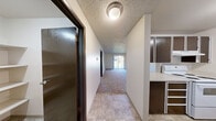 This Westwood unit in Steilacoom, Washington offers a practical and comfortable single-floor layout with two bedrooms, one bathroom, and two closets. The entry foyer features tile flooring and a textured ceiling, transitioning smoothly into the carpeted living and bedroom areas. A pass-through window connects the kitchen to the living room, creating an open feel between the two spaces. The kitchen is equipped with dark cabinetry and white appliances, including a range. The spacious living room benefits from natural light streaming through a sliding glass door that opens to an outdoor view, and is finished with a ceiling fan with light kit and plush carpeting throughout. The generously sized primary bedroom accommodates a comfortable living arrangement and is served by a well-appointed bathroom featuring wood-look flooring, a granite-topped vanity, a soaking tub, and a separate closet with a clothing rod. The second bedroom also features carpeting, a large window with outdoor views, and baseboard heating. Textured ceilings are a consistent design element throughout the unit, and neutral wall tones create a clean, versatile backdrop. This well-laid-out unit in Steilacoom provides a functional and cozy living environment.
