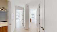 Located at 999 NW Seventh St in Miami's vibrant urban core, this well-appointed two-bedroom, two-bathroom residence offers a clean, contemporary design with an efficient and comfortable layout across a single floor. The open-concept kitchen serves as a visual centerpiece, featuring warm wood cabinetry paired with white upper cabinets and white quartz countertops, a central island with pendant lighting, stainless steel appliances, and a tasteful tile backsplash — all beneath soaring ceilings that amplify the sense of openness. Light-toned tile flooring flows seamlessly throughout the residence, enhancing its bright, airy ambiance. A wide hallway connects the living spaces to both bedrooms, each of which benefits from large floor-to-ceiling sliding glass doors that open to balcony views of the surrounding Miami cityscape, flooding the rooms with natural light. The primary bedroom includes a dedicated walk-in closet outfitted with wire shelving for organized storage. The two bathrooms are finished in clean white tile — one featuring a soaking tub with a shower combo, and the other a glass-enclosed walk-in shower — both with chrome fixtures and a minimalist aesthetic. The overall design emphasizes modern simplicity, natural light, and urban connectivity.