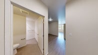Located at 4302 7th Ave NE in Seattle's vibrant University District, this efficiently designed single-floor unit makes smart use of its compact footprint. The open layout is anchored by light hardwood-style flooring that runs throughout the main living area, creating a clean and cohesive aesthetic.

The kitchen is a functional highlight of the space, outfitted with warm wood cabinetry, white countertops, and a full suite of stainless steel appliances including a refrigerator, range, microwave, and dishwasher. Track lighting above the kitchen ensures well-lit meal preparation, while a double-pane window alongside the kitchen area invites natural light and views of the surrounding greenery.

The hallway connects the main living zone to the bathroom and additional storage areas, finished with neutral carpet and clean white walls for a bright, open feel. The bathroom features a wood-toned vanity with an integrated sink and access to a separate carpeted closet or utility area. A HVAC vent system ensures year-round climate comfort throughout the unit.

The main living area offers a versatile, open canvas with hardwood-style flooring, white walls, and natural light filtering in from nearby windows. This well-organized unit provides a practical and comfortable living environment in one of Seattle's most walkable and transit-accessible neighborhoods.