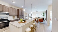 This thoughtfully designed 2-bedroom, 2-bathroom residence offers a cohesive open-concept layout that maximizes both functionality and comfort. Light wood-tone flooring flows seamlessly throughout, complementing the warm, neutral palette found in every room.

The kitchen and living area form the heart of the home, anchored by a large central island with granite countertops, double undermount sink, and seating for multiple bar stools. Rich dark-espresso cabinetry, a white subway tile backsplash, stainless steel appliances, and elegant pendant lighting complete the kitchen. The adjacent living room is bright and welcoming, with large windows dressed in slatted blinds that allow generous natural light, a ceiling fan, and ample space for comfortable seating arrangements.

The primary bedroom provides a private retreat with direct access to its own bathroom, which features granite-topped dual vanities with dark cabinetry, light tile flooring, and a tub-shower combination with marble-style tile surround. A spacious walk-in closet with wire shelving offers generous storage. The second bedroom is equally well-lit, with ceiling fan and access to a second full bathroom sharing the same refined finishes. Additional highlights include multiple closets, a dedicated laundry area, and a utility room, ensuring practical storage throughout the residence.