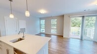 Located at 83 Pleasant Valley St in Methuen, MA, this two-bedroom, three-bathroom residence offers a well-designed single-floor layout with a clean, contemporary aesthetic throughout. The open living area is anchored by warm hardwood-style flooring and large windows that flood the space with natural light, offering views of the surrounding community grounds and greenery.

The modern kitchen is a standout feature, centered around a spacious white quartz island with an integrated sink. Taupe flat-front cabinetry pairs with a white subway tile backsplash, and stainless steel appliances—including a refrigerator, range, and microwave—complete the functional and stylish design. Pendant lighting with brass accents adds a refined touch overhead.

Both bedrooms feature plush carpeting and generous windows. The primary bedroom is well-proportioned and is accompanied by a dedicated bathroom with a wood-toned vanity, white quartz countertop, and tile flooring. An additional bathroom includes a full tub and shower combo finished with classic white subway tile. A walk-in closet with wire shelving and hanging rods provides organized storage.

The third bathroom offers additional convenience for guests. Neutral wall tones and consistent finishes throughout create a cohesive, move-in-ready living environment.