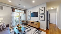 Located at 5 Kensington Ln in Rocky Hill, Connecticut, this one-bedroom, one-bathroom residence offers a thoughtfully designed single-floor layout with a cohesive, modern aesthetic throughout. The living room is a welcoming focal point, featuring warm hardwood flooring, recessed lighting, and a sliding glass door that opens to a private balcony, allowing natural light to fill the space and providing views of the surrounding community. The kitchen is well-appointed with rich cherry wood cabinetry, granite countertops, stainless steel appliances including a gas range and built-in microwave, and hardwood flooring that flows seamlessly into the adjacent dining area. The dining space is accented by a pendant chandelier and chair rail molding, lending a refined touch. The bedroom offers a comfortable retreat with plush carpeting, a walk-in closet, and soft neutral tones complemented by textured accent walls. The bathroom includes tile flooring, a full soaking tub and shower combination, a cherry wood vanity with a framed mirror, and clean, understated finishes throughout. Overall, the residence presents a functional and stylish living environment well-suited for comfortable everyday living.