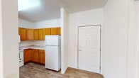 This single-floor, 2-bedroom, 2-bathroom residence offers a practical and well-organized layout across a comfortable footprint. The combined kitchen and living area forms the heart of the home, featuring an open-concept kitchen with warm honey-toned wood cabinetry, ample upper and lower cabinet storage, white appliances including a refrigerator, electric range, and over-the-range microwave, and light countertops. A peninsula with a breakfast bar separates the kitchen from the carpeted living area, creating a natural flow between spaces. Wood-look flooring runs through the kitchen and entry areas, adding warmth and durability.

Both bedrooms are carpeted and finished with neutral white walls, offering a clean and versatile canvas. The primary bedroom provides a generous amount of space, while both rooms benefit from natural light through windows. The two bathrooms are fitted with wood-toned vanities and wood-look flooring, maintaining a consistent design aesthetic throughout.

A dedicated closet with wire shelving and hanging rods provides organized storage. The in-unit laundry room accommodates a full-size washer and dryer side by side, complete with additional wire shelving above—a highly convenient feature. The overall ambiance of this residence is clean, bright, and move-in ready.